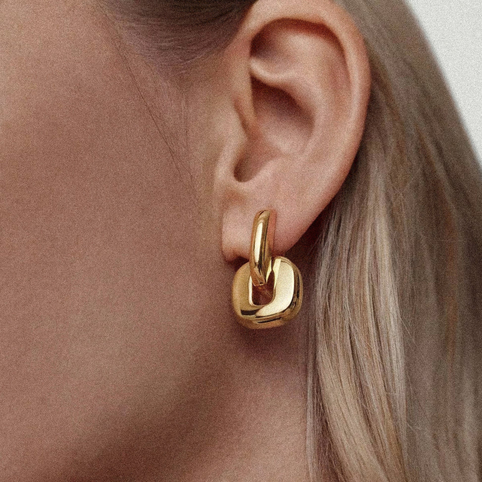 Gold hoop earring worn by a woman with fair skin and blonde hair.