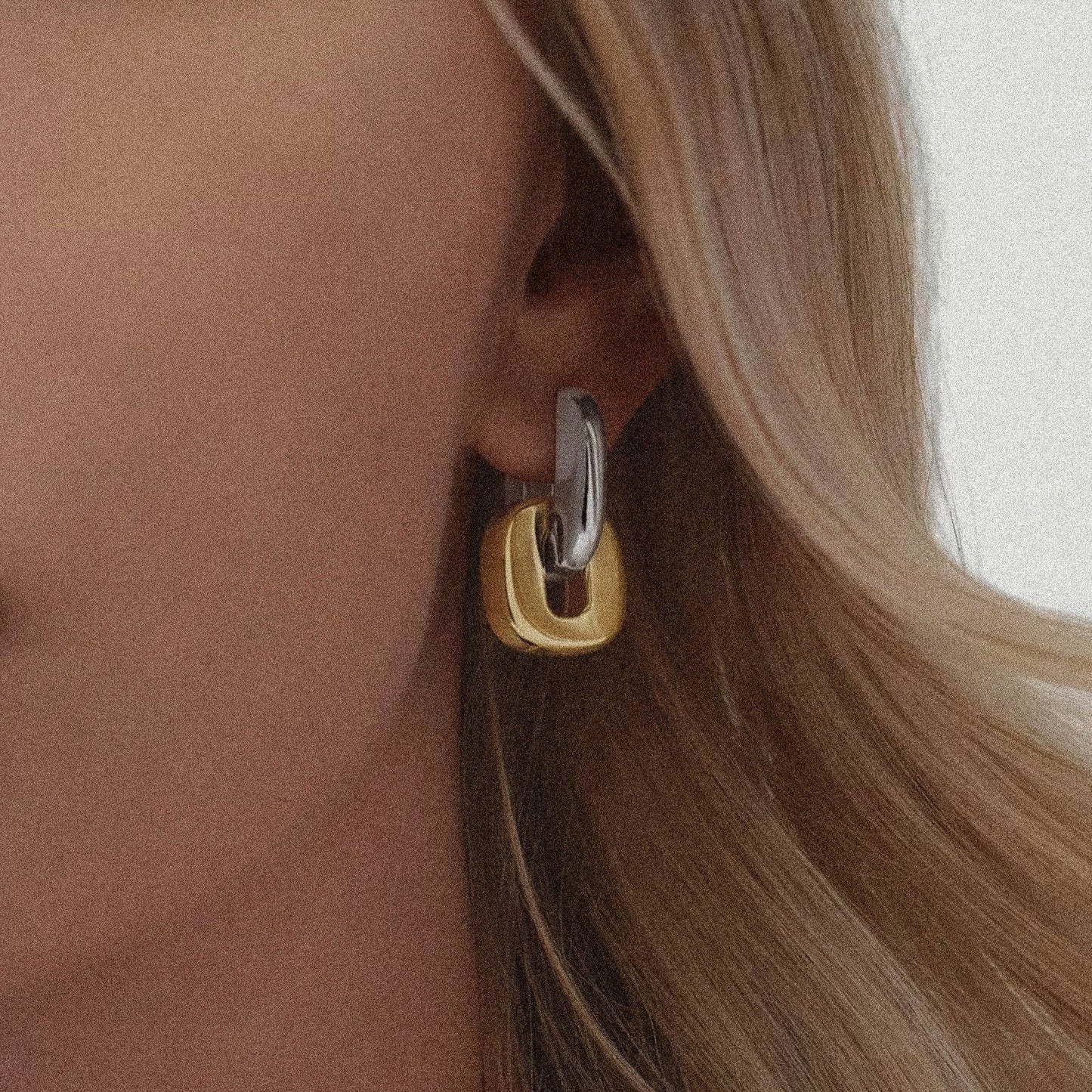 Close-up of a woman wearing a gold and silver hoop earring.