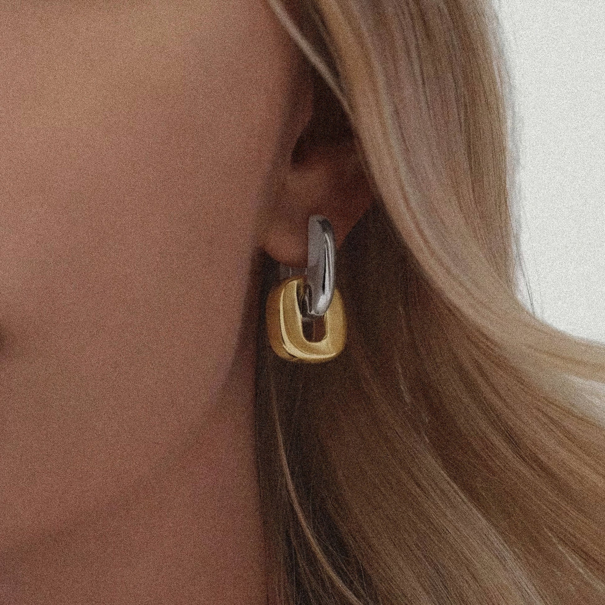 Close-up of a woman wearing a gold and silver hoop earring.
