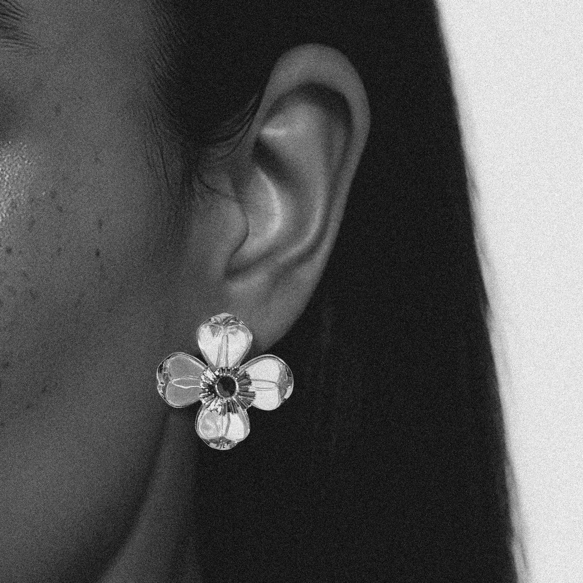 Close-up of a floral earring worn on an ear with a blurred background