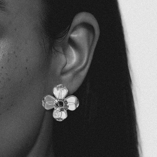 Close-up of a floral earring worn on an ear with a blurred background