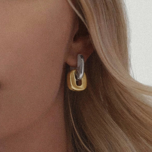 Close-up of a woman wearing a gold and silver hoop earring.